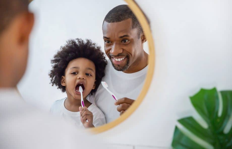 man and boy brush teeth in mirror