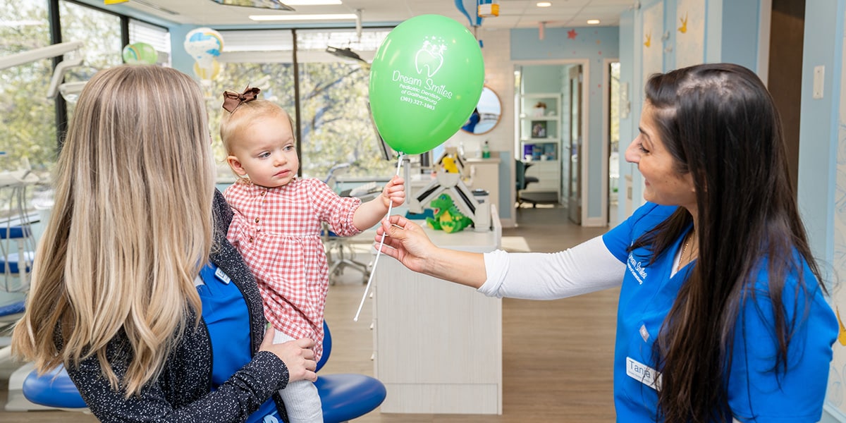 employee handing little girl a balloon